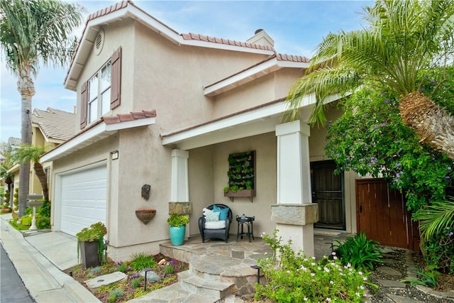 mediterranean / spanish-style home with a tiled roof, an attached garage, and stucco siding