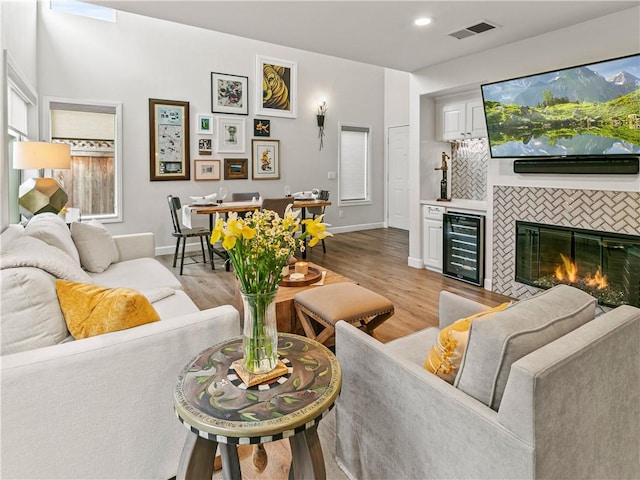 living room with wine cooler, baseboards, light wood-style flooring, and visible vents