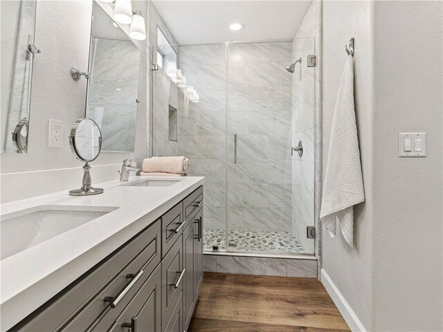 full bath with a sink, double vanity, recessed lighting, wood finished floors, and a stall shower