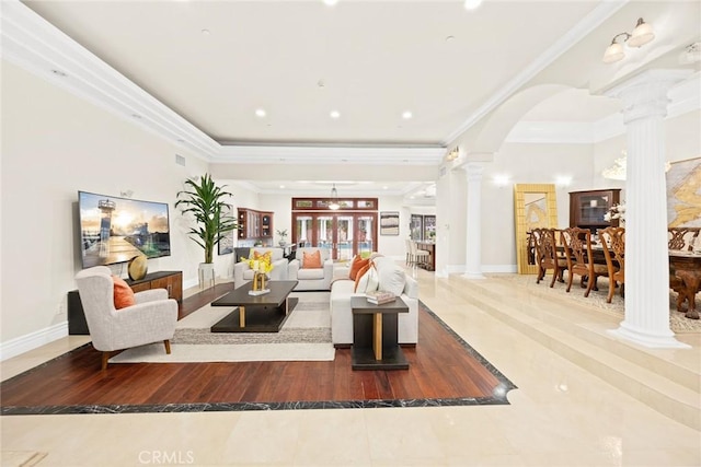 living room featuring arched walkways, wood finished floors, baseboards, ornate columns, and crown molding