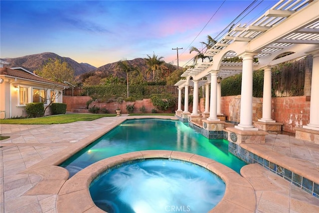 view of swimming pool with a pergola, a pool with connected hot tub, a patio area, a fenced backyard, and a mountain view