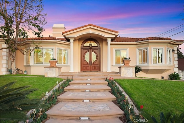1774 Orangewood Ln, Arcadia, CA 91006 - exterior entry at dusk with stucco siding, a tiled roof, and a lawn