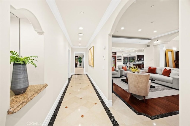 hall featuring crown molding, arched walkways, baseboards, recessed lighting, and ornate columns