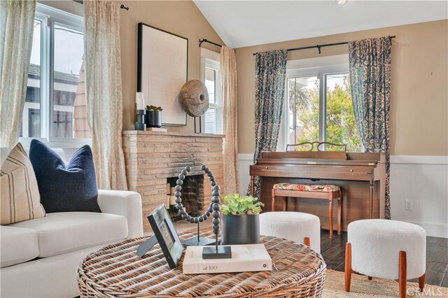 sitting room with wood finished floors, lofted ceiling, and a healthy amount of sunlight
