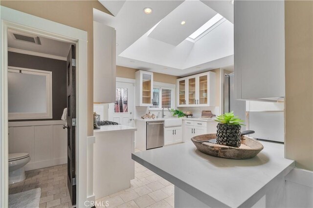 kitchen featuring glass insert cabinets, visible vents, stainless steel dishwasher, a skylight, and white cabinets