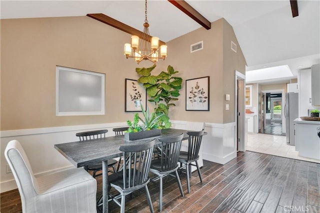 dining room with a notable chandelier, visible vents, dark wood-style flooring, and high vaulted ceiling