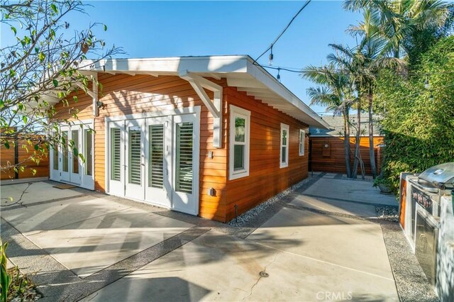 view of property exterior with a patio, fence, and french doors