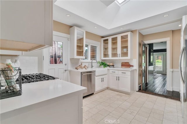 kitchen featuring dishwasher, white cabinets, decorative backsplash, and light countertops