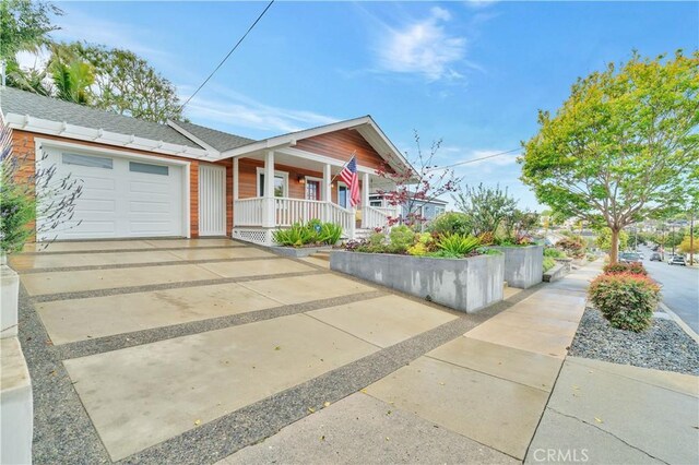 single story home with a porch, driveway, a garage, and roof with shingles