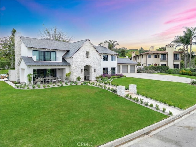 view of front of property with a front yard, a garage, stone siding, a chimney, and stucco siding