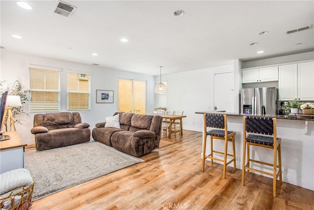 living area featuring light wood-style floors, recessed lighting, and visible vents
