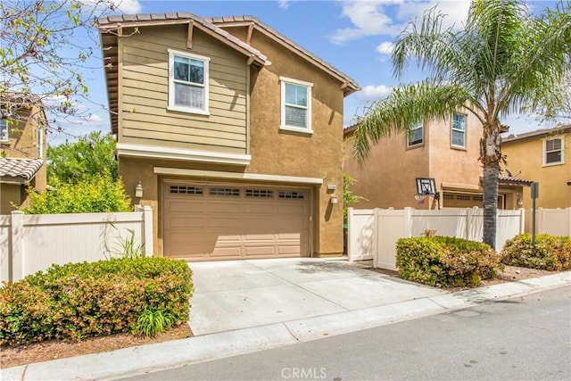 traditional-style house featuring an attached garage, stucco siding, driveway, and fence