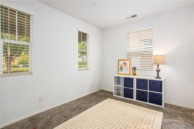 carpeted spare room featuring baseboards, plenty of natural light, and visible vents
