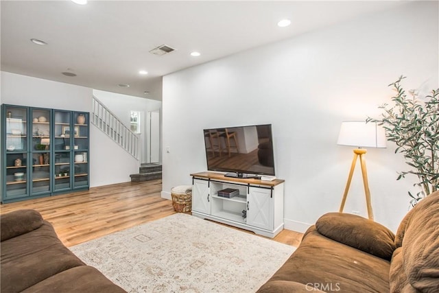 living area featuring visible vents, light wood-style floors, baseboards, stairway, and recessed lighting