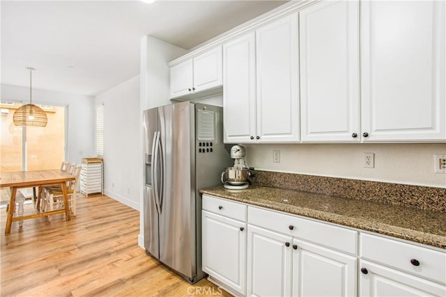 kitchen featuring dark stone counters, white cabinetry, stainless steel fridge, and light wood finished floors