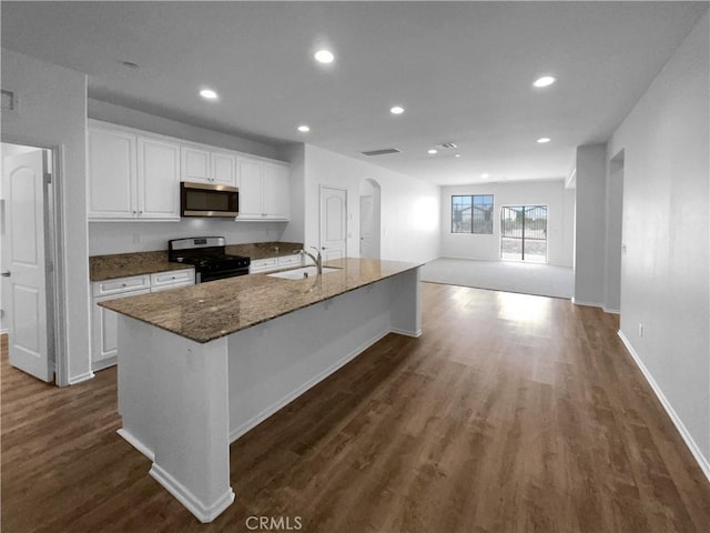 kitchen featuring dark wood finished floors, a sink, white cabinets, dark stone counters, and stainless steel appliances