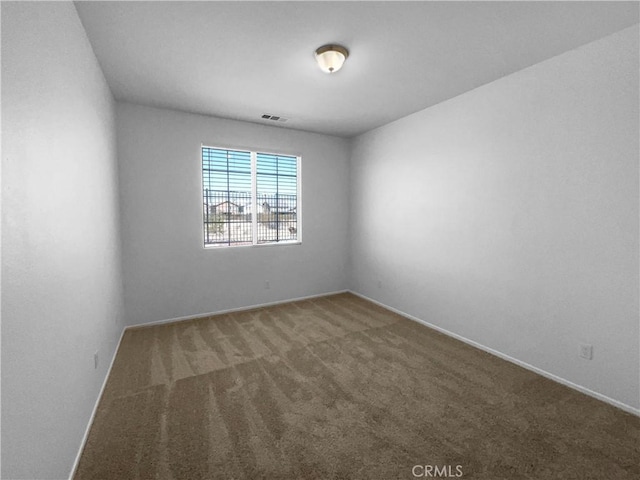 spare room featuring baseboards, visible vents, and carpet
