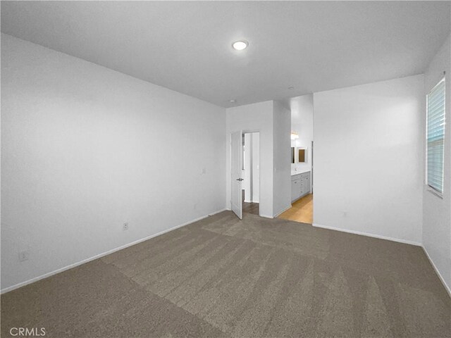 unfurnished bedroom with carpet floors, baseboards, and ensuite bathroom