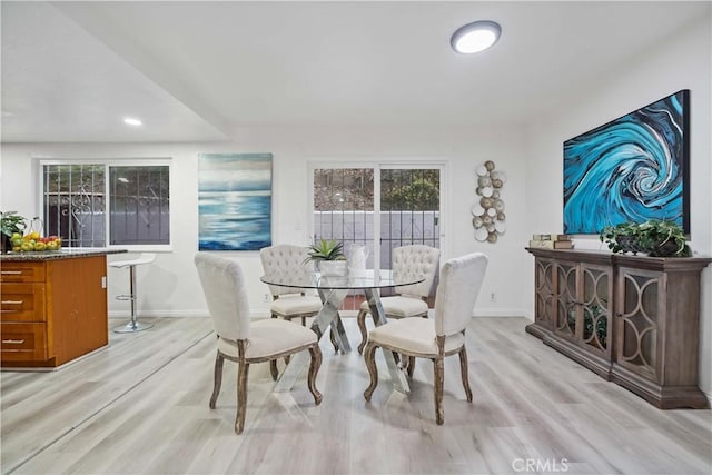 dining area featuring baseboards, a healthy amount of sunlight, and light wood finished floors