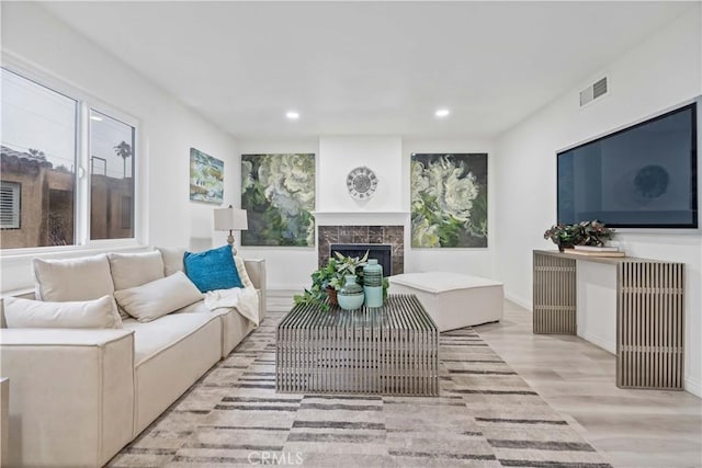 living room with recessed lighting, light wood finished floors, a fireplace, baseboards, and visible vents