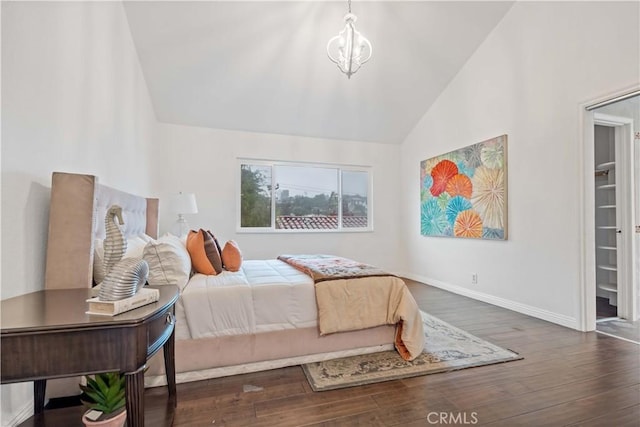 bedroom with a notable chandelier, wood finished floors, lofted ceiling, and baseboards