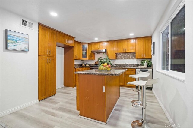 kitchen with recessed lighting, brown cabinets, visible vents, a kitchen island, and stainless steel dishwasher