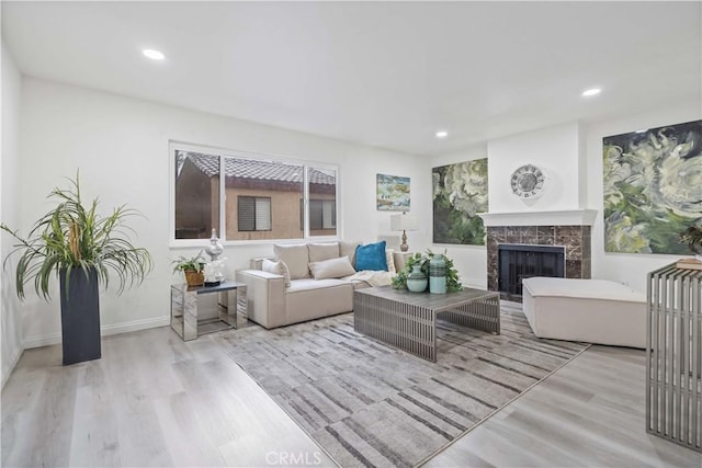 living room featuring baseboards, recessed lighting, wood finished floors, and a tile fireplace