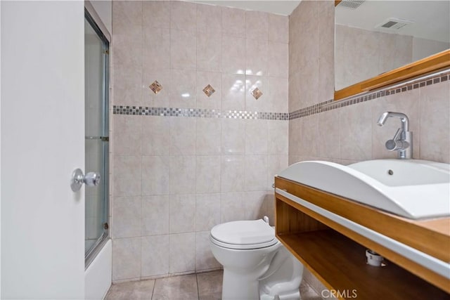 full bathroom featuring tile walls, toilet, tile patterned flooring, and combined bath / shower with glass door