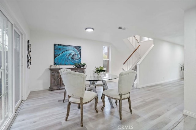 dining space with wood finished floors, visible vents, stairs, and baseboards