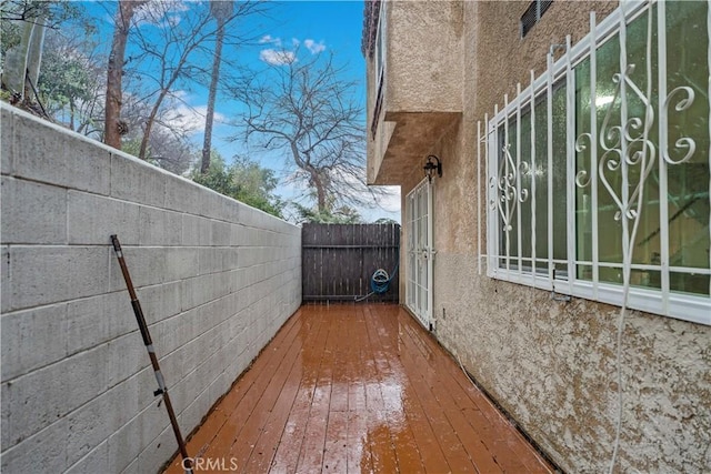view of side of property with stucco siding, fence, and a wooden deck