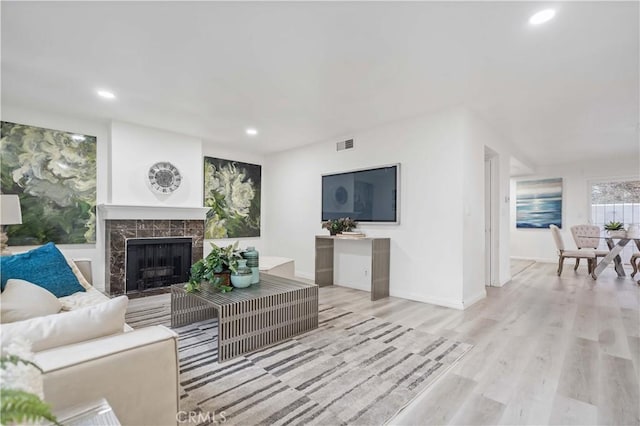 living room with recessed lighting, wood finished floors, a high end fireplace, baseboards, and visible vents