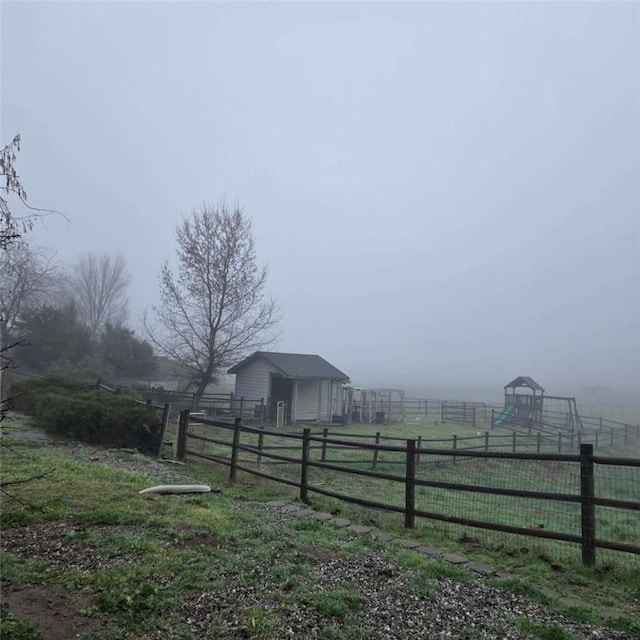 view of yard with fence, a rural view, and an outbuilding