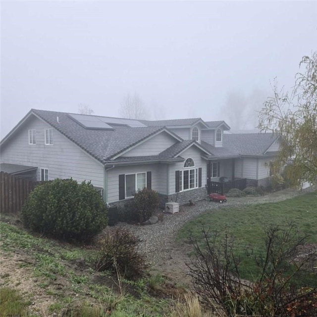 view of home's exterior featuring fence, a shingled roof, and a yard