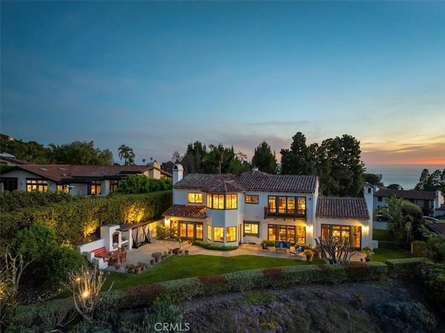 2839 Via Victoria, Palos Verdes Estates, CA 90274 - back of property at dusk featuring a patio area, a tiled roof, stucco siding, a chimney, and a lawn