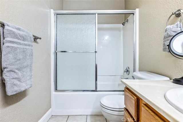 full bathroom with tile patterned flooring, shower / bath combination with glass door, toilet, a textured wall, and vanity