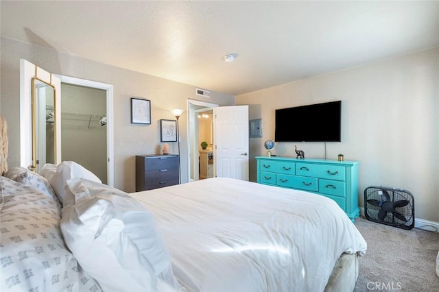 carpeted bedroom featuring baseboards, visible vents, and a walk in closet