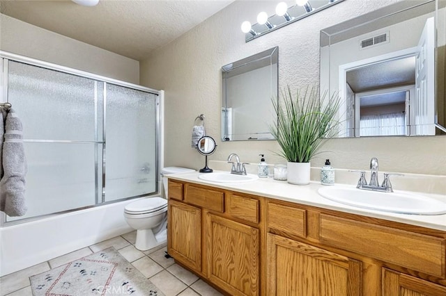 full bath featuring a textured wall, toilet, visible vents, and a sink