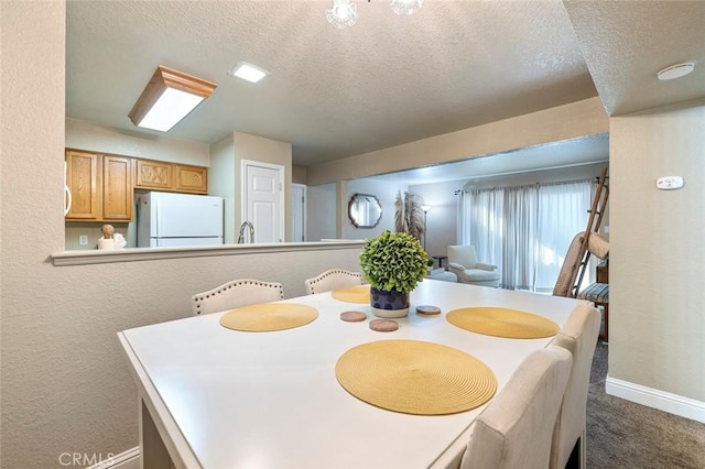 dining room with dark colored carpet, a textured ceiling, a textured wall, and baseboards