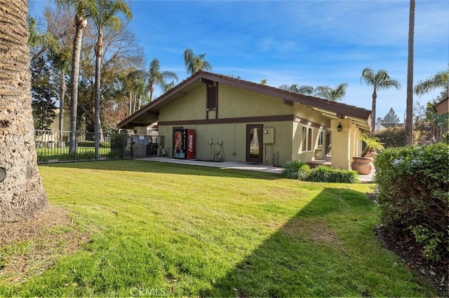 rear view of house with fence, stucco siding, a yard, and a patio area