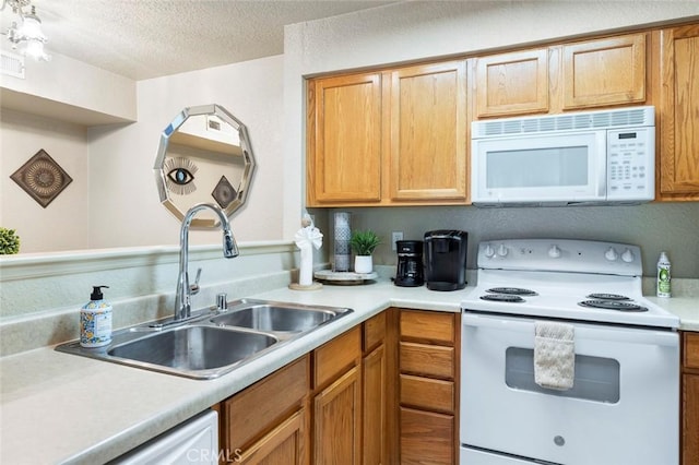 kitchen with white appliances, a textured ceiling, light countertops, and a sink