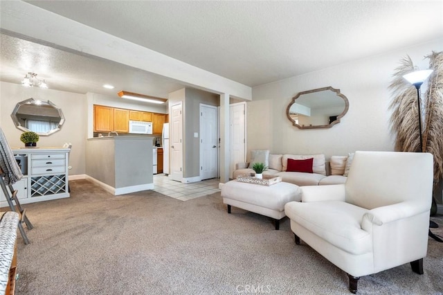 living room with a textured ceiling, light carpet, and baseboards