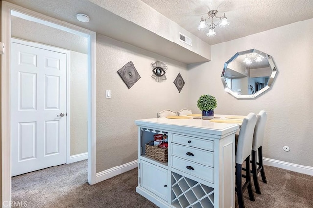 interior space with an inviting chandelier, a textured wall, baseboards, visible vents, and a textured ceiling