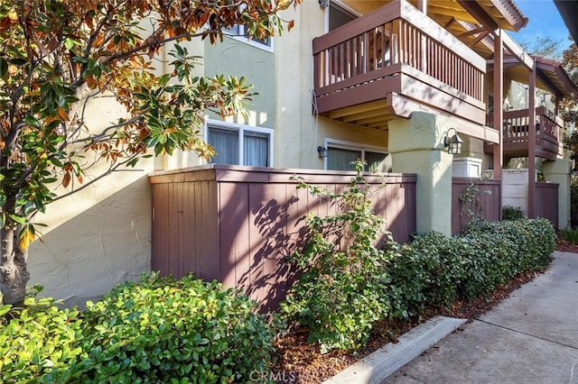 view of home's exterior with fence, a balcony, and stucco siding