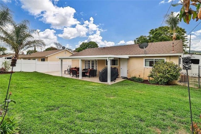 back of house with stucco siding, fence, a patio area, and a yard