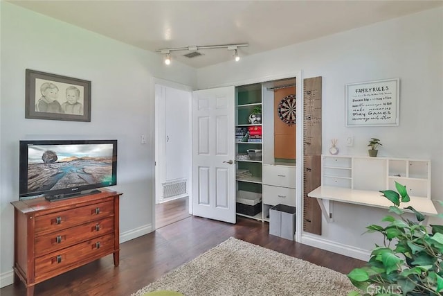 bedroom with track lighting, dark wood-style flooring, and baseboards