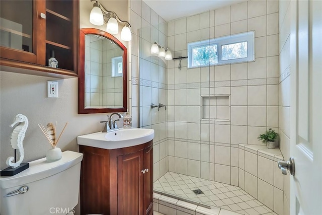 full bath featuring toilet, a tile shower, and vanity