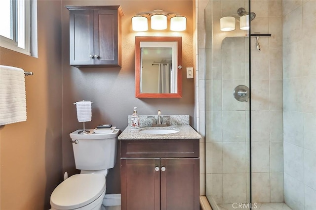 bathroom featuring toilet, tiled shower, and vanity