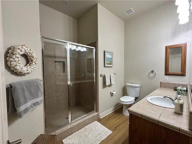 full bath with vanity, toilet, a stall shower, visible vents, and wood finished floors