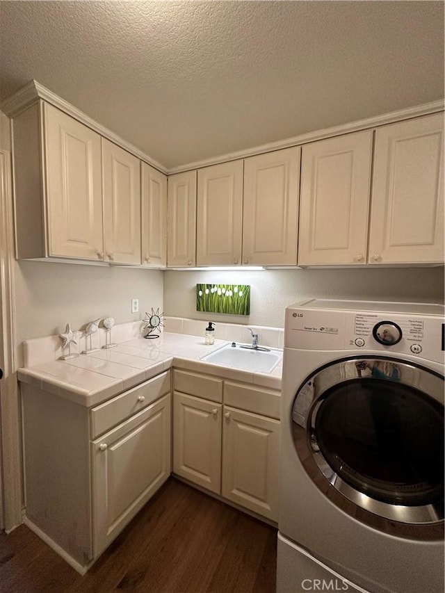 washroom with dark wood finished floors, cabinet space, washer / dryer, a sink, and a textured ceiling