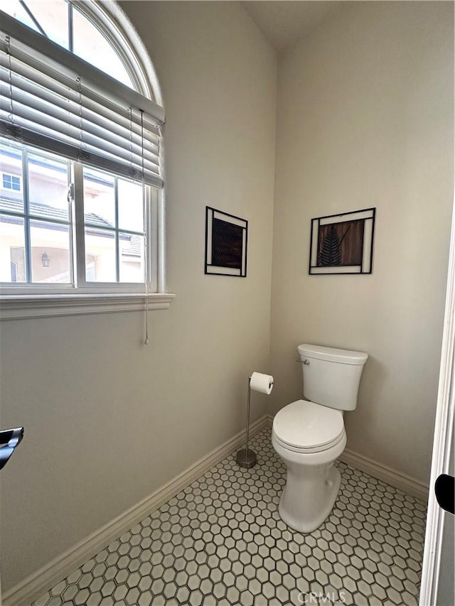 bathroom featuring baseboards, a wealth of natural light, and toilet
